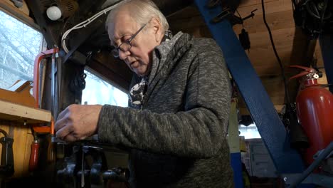 senior mechanic uses vernier caliper to measure machine part held in a bench vice