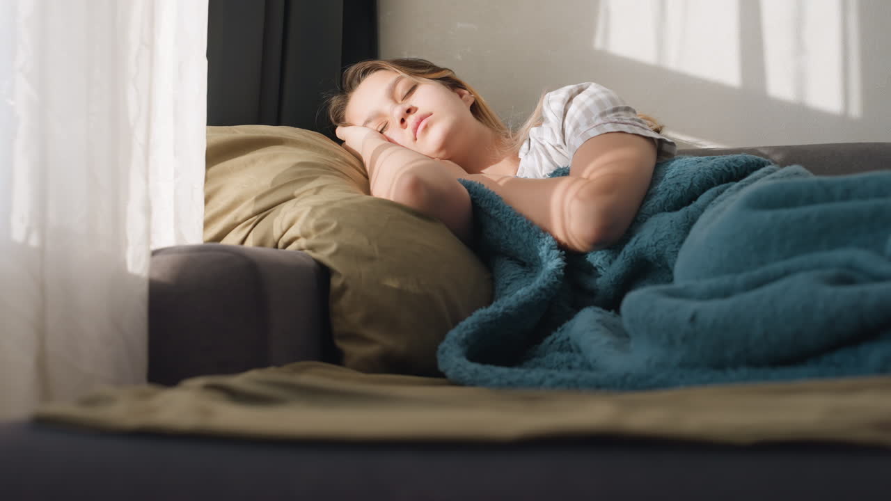 Serene Woman Dozing In Bright Room Atmosphere, Calm Woman Naps Comfortably In Sunfilled Cozy Space, Tranquil Woman Relaxing Peacefully On Sofa Illuminated By Sunlight And Warm Surroundings