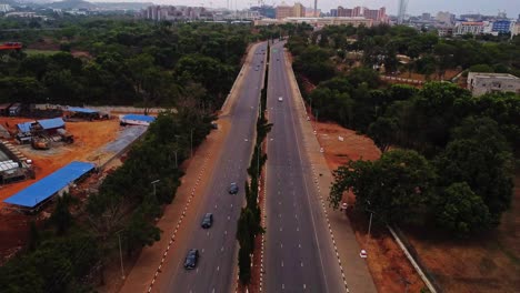 high angle view of cars driving over a long road with the skyline of abuja, the capital city of nigeria, in the background