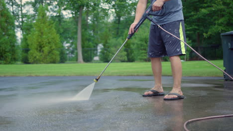 cropped image of a man cleaning asphalt ground with a pressure washer