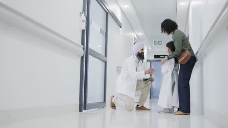 happy biracial doctor talking to girl with mother in hospital in slow motion