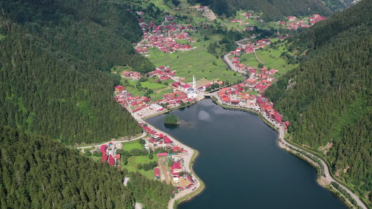 vista aérea de arriba hacia abajo de un pueblo de montaña lleno de casas con techos rojos rodeados de montañas y una mezquita cerca de un gran lago ubicado en uzungol trabzon turquía en un día soleado de verano