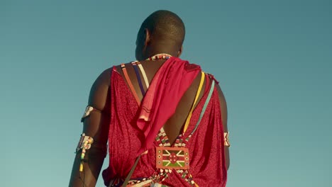 parte trasera de un joven guerrero masai que viste ropa tradicional en una tribu en kenia