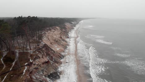 Aerial-shot-waves-waves-crushing-on-sandy-beach-in-Ustka-in-winter