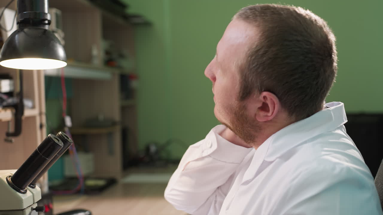 색 실험실 코트 를 입은 기술자 가 목 을 고 마사지 하는 근접 한 모습