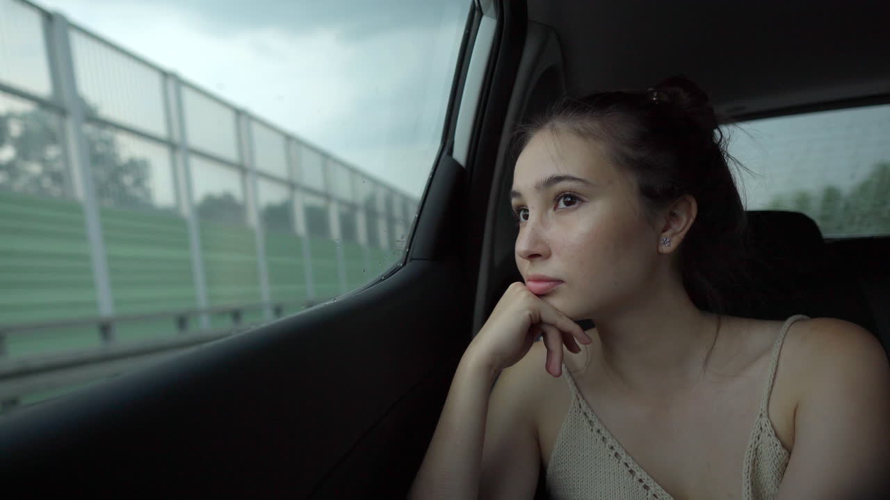 자동차 창문 밖을 바라보는 사려 깊은 젊은 여성