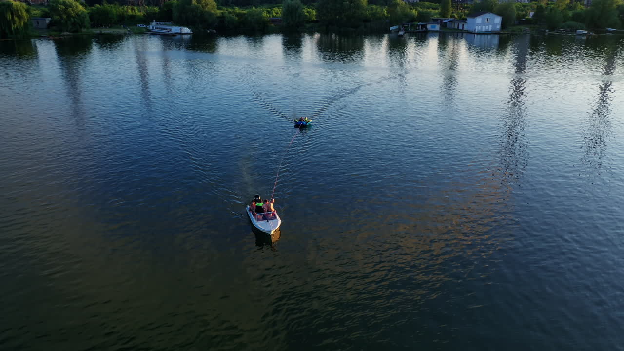 White boat on the river at sunset. People sailing in boats among beautiful landscape in the evening. Rest in summer. Aerial view.