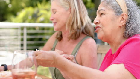 Mujer-Caucásica-Y-Mujer-Birracial-Mayor-Disfrutan-De-Una-Comida-Al-Aire-Libre