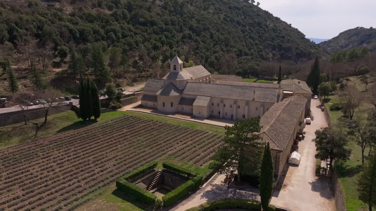 Vista aerea di un'abbazia francese incorniciata da terra dorata e file di lavanda tagliata