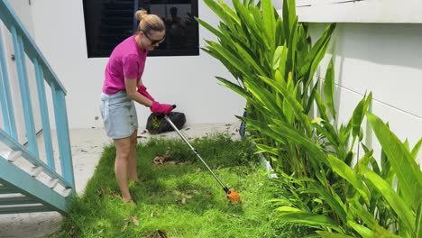 mujer cortando el césped en el patio trasero