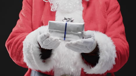 Video-of-santa-claus-holding-christmas-present-with-copy-space-on-black-background