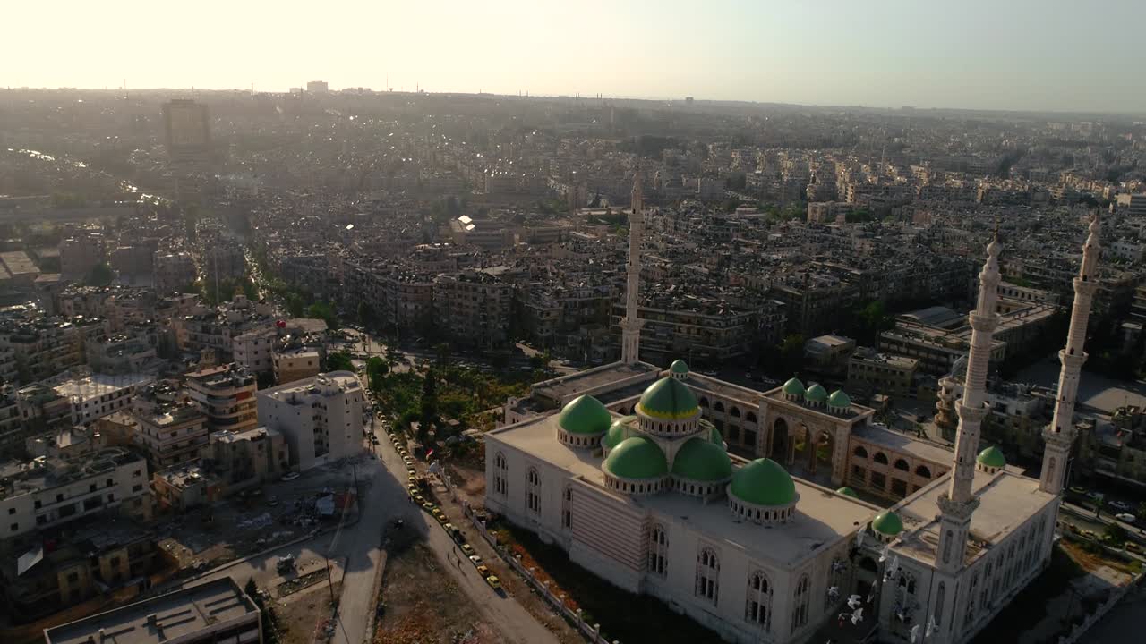 vista aérea de la hermosa mezquita de alepo reconstruida después de la guerra civil, bajo la puesta de sol. podemos ver las ruinas de la ciudad en el fondo 4k