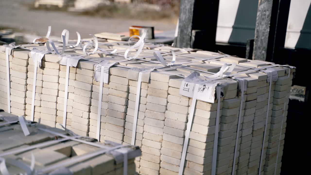 an automatic trolley is stacking pallets with bricks next to each other in the street near the factory. Professional warehouse equipment