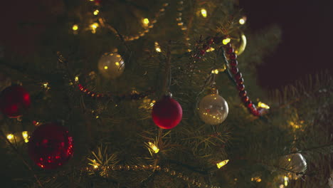 a person hangs a bulb on a christmas tree