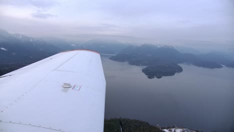 Blick-Auf-Den-Flügel-Eines-Leichten-Flugzeugs,-Das-über-Den-Bergsee-Fliegt---Bewölkter-Tag