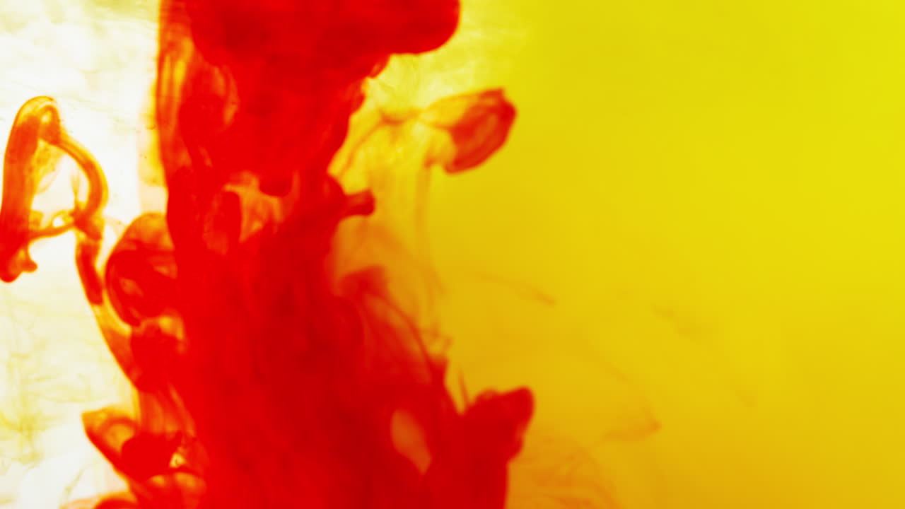 빨간색과 노란색 페인트 또는 염료가 색 배경에 물에 떨어지면서 회전하는 다채로운 연기 배경을 만니다.