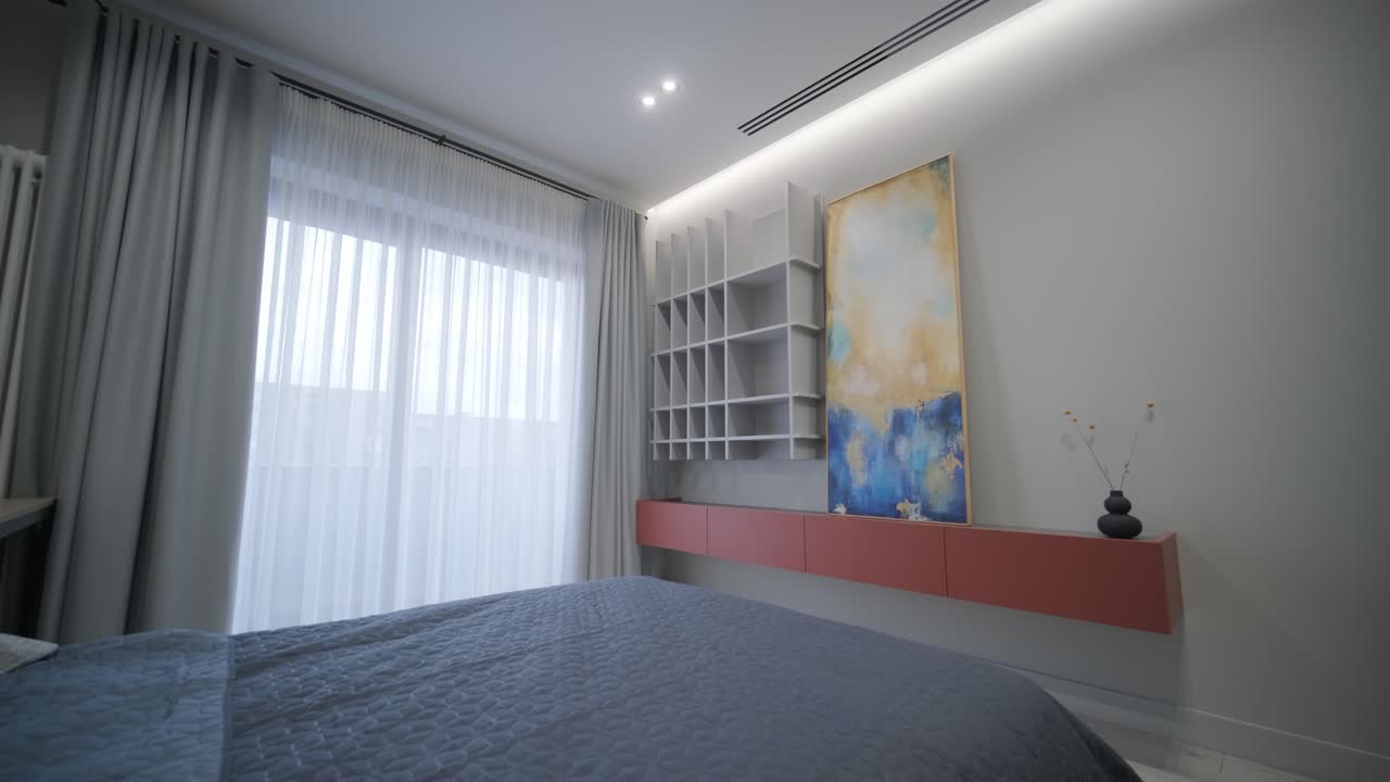 dormitorio tranquilo con una cubierta de cama azul, arte moderno y estanterías elegantes contra cortinas transparentes