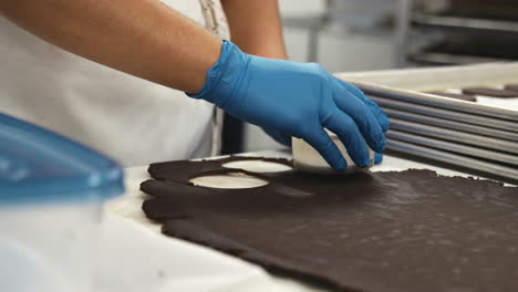 baker cutting out circles of cookie dough, close up