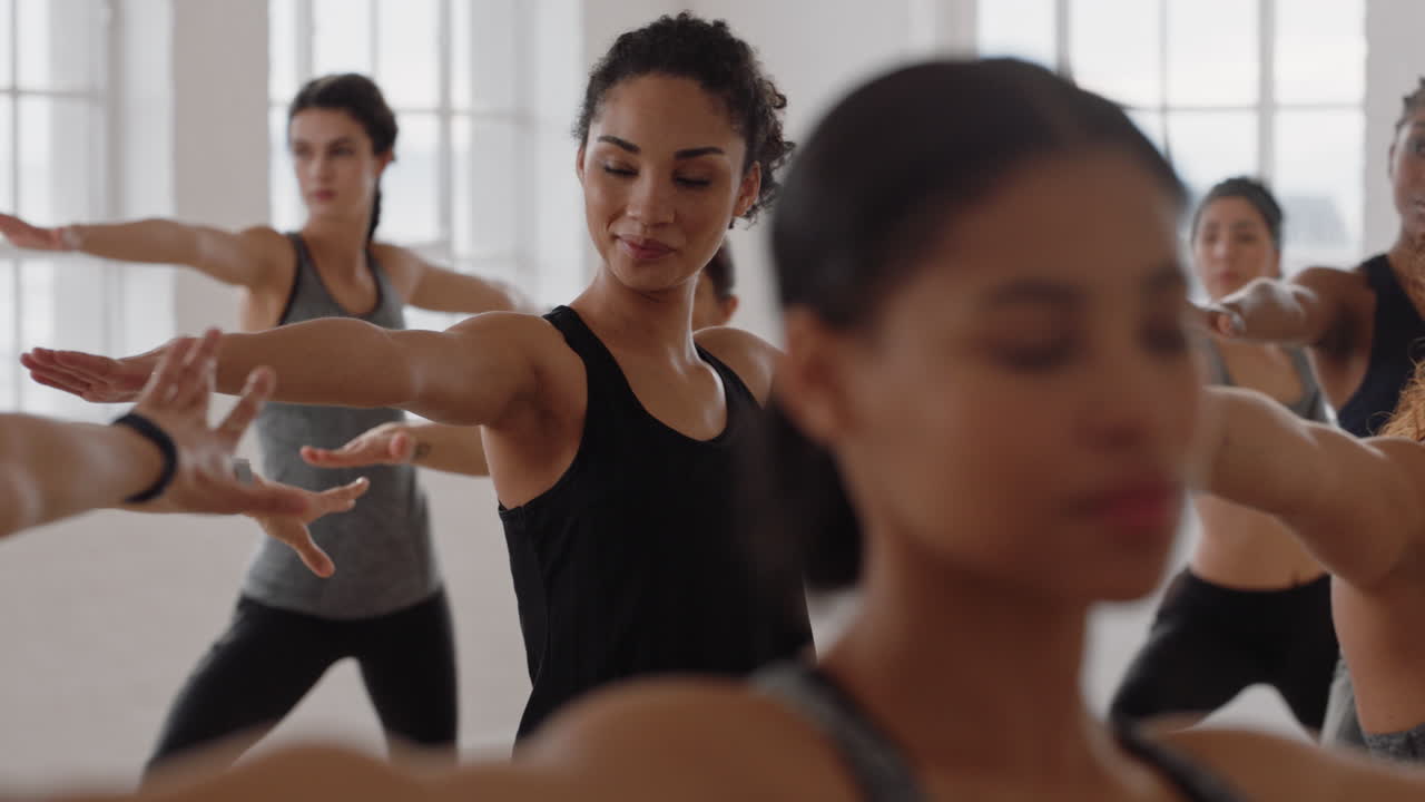 beautiful yoga woman instructor teaching reverse warrior pose meditation with group of multiracial women enjoying healthy lifestyle exercising in fitness studio at sunrise