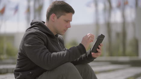 concentrated young man using tablet pc outdoor