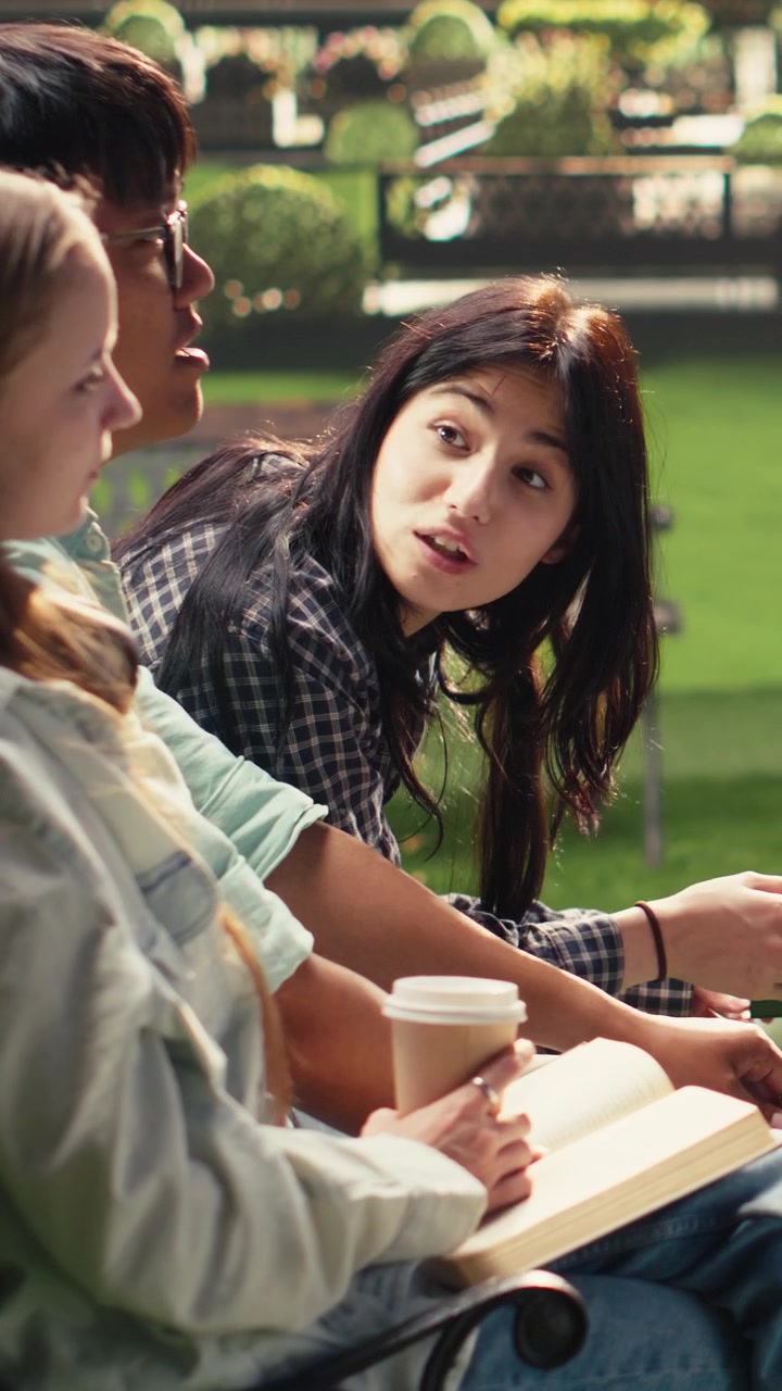 Vertical Video Students gathering around open laptop with books and coffee cups