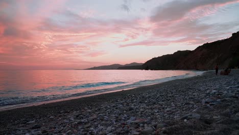 puesta de sol roja en una playa de guijarros