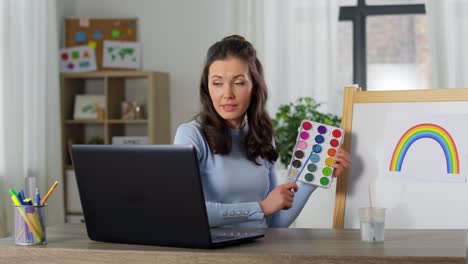 Lehrerin-Mit-Farben,-Die-Online-Kunstunterricht-Hat.-Fernunterricht,-Grundschule-Und-Unterrichtskonzept.-Lehrerin-Mit-Farben-Und-Einem-Bild-Eines-Regenbogens,-Die-Zu-Hause-Online-Kunstunterricht-Hat.