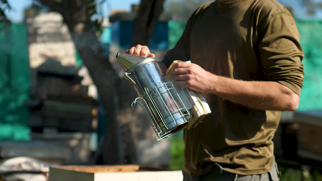 Beekeeper preparing bee smoker to calm down the bees