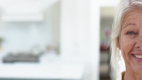 half face of happy caucasian senior woman standing and laughing in sunny room at home, slow motion