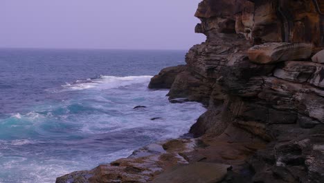 waves rushing towards the beautiful rock formation of the bronte beach in australia - slow motion