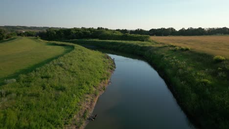 aerial above narrow creek between grassy fields