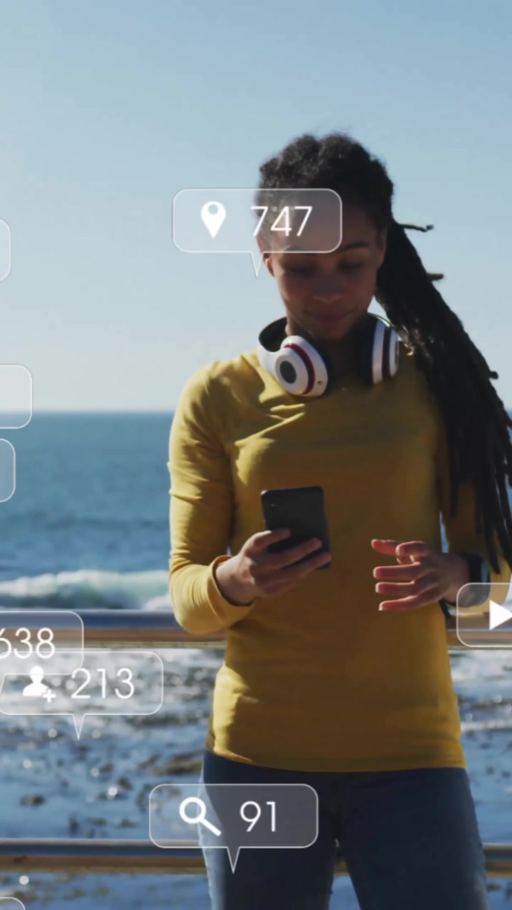 Social media interaction icons animation over woman using smartphone by ocean