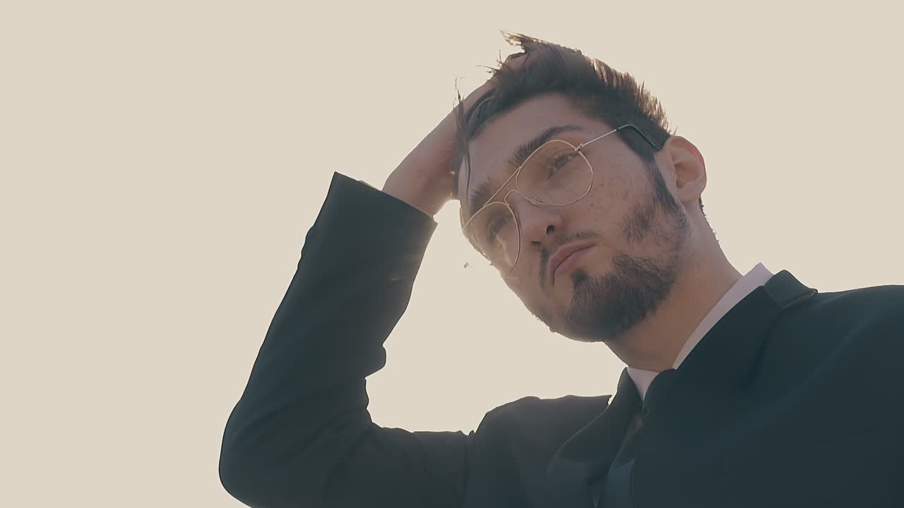 uomo con gli occhiali fissa i capelli che ondeggiano nel vento in slow motion