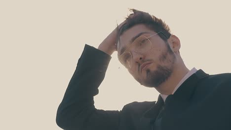 man in glasses fixes hair waving in wind slow motion