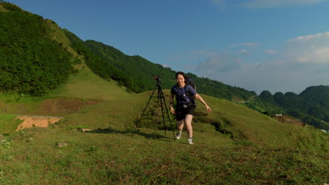 young-solo-female-traveller-taking-a-selfie-with-a-camera-on-tripod-for-her-social-media-during-a-backpacker-trip-on-mountains-travel-destination