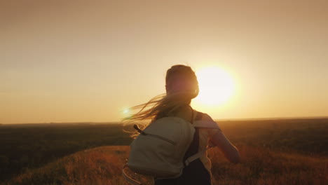 un niño de pelo largo con una mochila corre hacia el sol, los sueños de los niños y el concepto de vacaciones