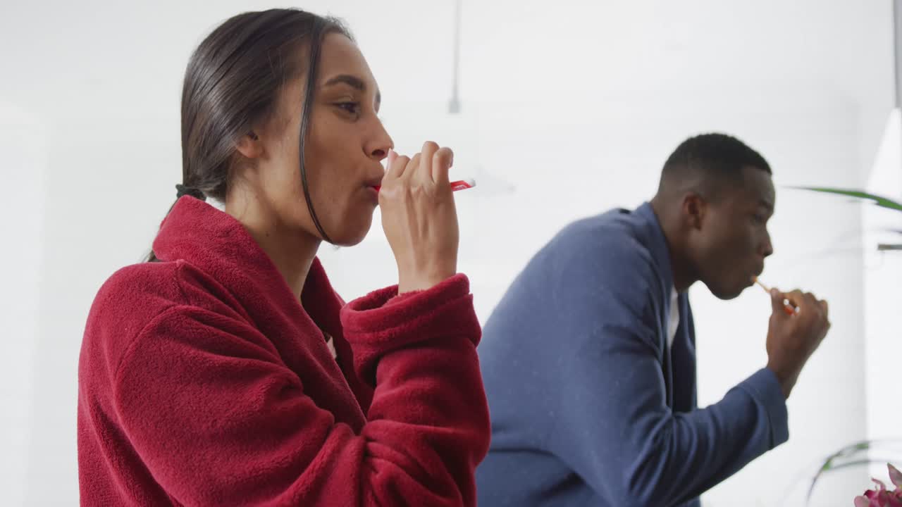 video de una feliz pareja diversa cepillándose los dientes en el fregadero en el baño en casa