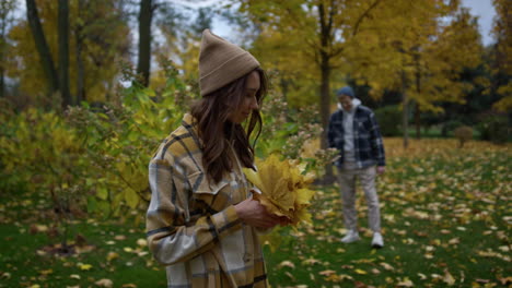 Close-up-view-of-dreaming-stylish-girl-holding-autumn-leaves-in-october-park.