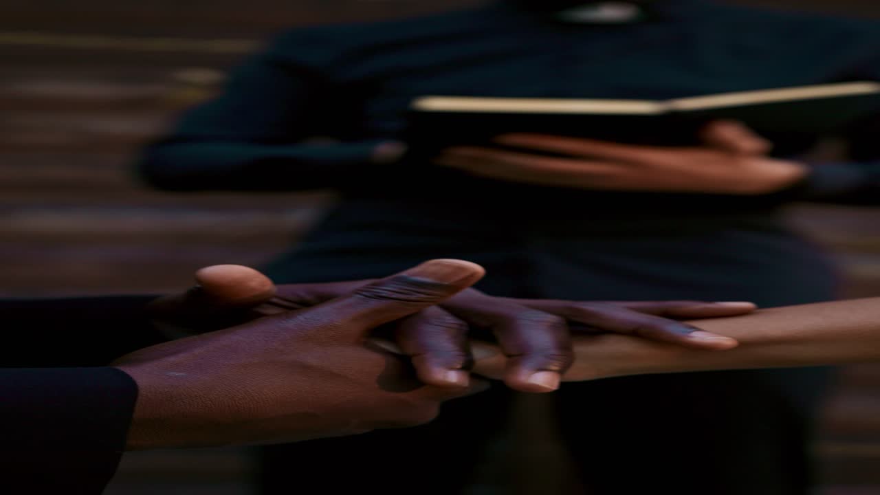 An interracial couple prays with a priest