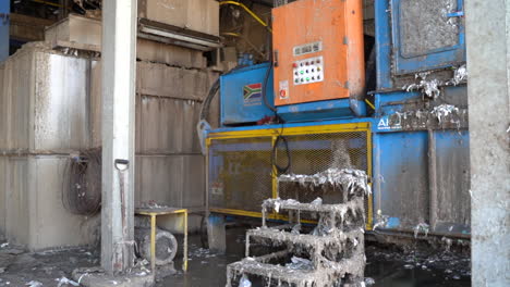 cinematic-shot-of-recycling-plant-machinery-with-paper-pulp-on-conveyor-with-a-South-African-flag