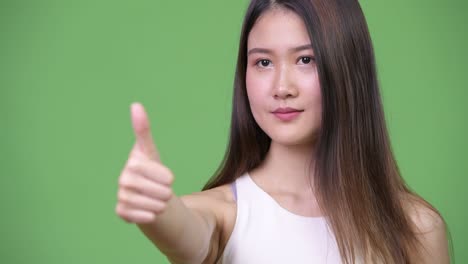 젊은 아름다운 아시아 사업가 여성이 엄지손가락을 올리고 있습니다.