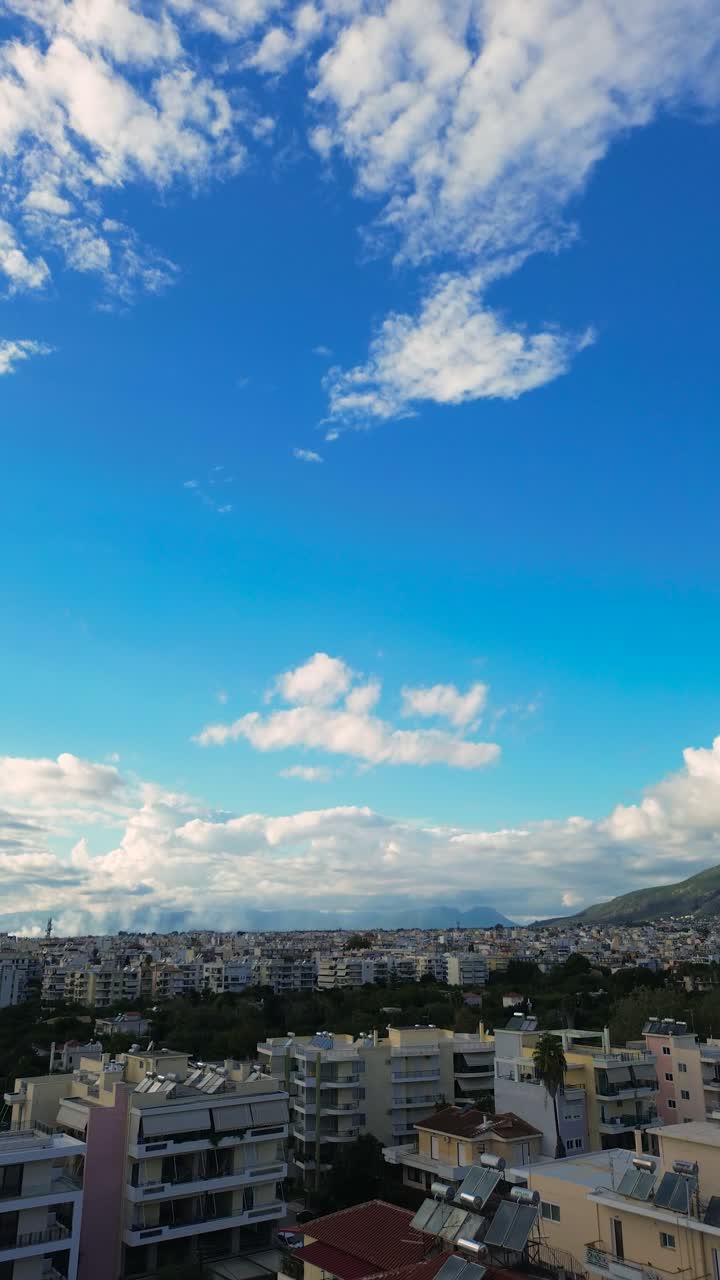 Aerial. raise up, tilt down high angle cityscape of Kalamata city, Messinia, Peloponnese , Greece. Establishing reveal vertical shot, transition from cloudy blue sky to cityscape 4K
