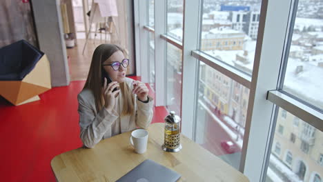 friendly talk on the phone in a spacious office. lady in light clothes speaks on the phone being in a good mood. high angle view.