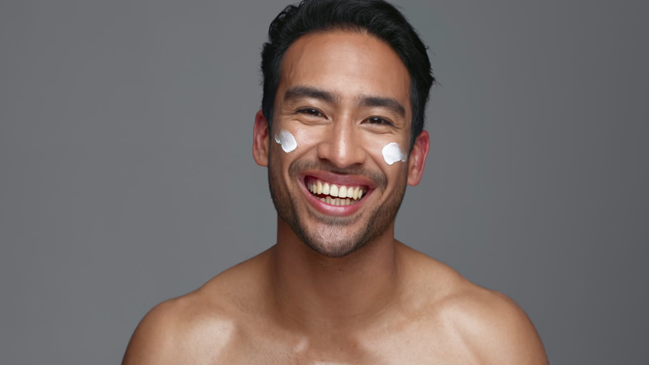 Face, man and apply of moisturiser in studio