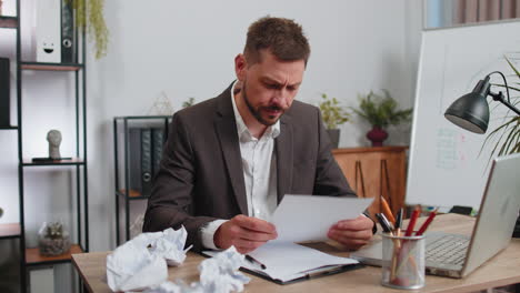 angry furious man working at home office throwing crumpled paper, having nervous breakdown at work