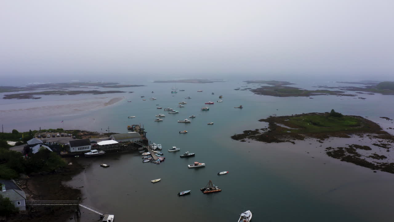 Ripresa aerea con drone in allontanamento di un porto turistico oceanico con pescherecci per aragoste e isole 4k 30p