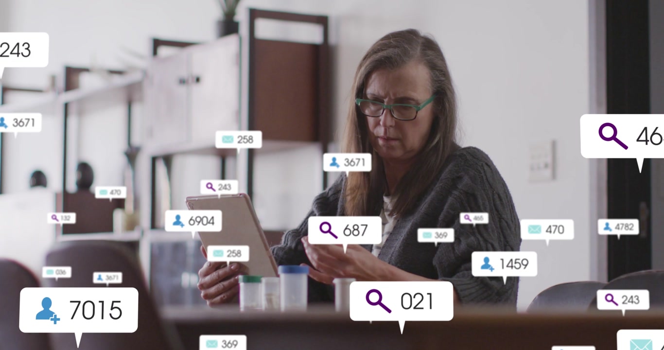 Mature woman tapping tablet comparing greencap bottle, health icons overlaying table, aiding meds