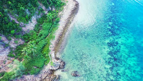 Colorful-seabed-on-shoreline-of-tropical-island-with-coral-reefs-under-turquoise-water-washing-rocky-coast-in-Cambodia