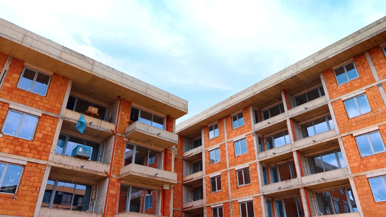 Vista en contrapicado de un edificio residencial de ladrillo. Vista en contrapicado de un edificio de apartamentos en construcción con ladrillos cerámicos naranjas y estructuras de hormigón.