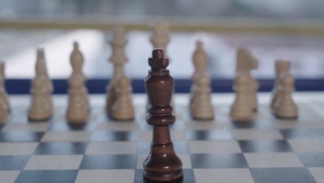 Black-King-Chess-piece-stands-alone-in-front-of-white-army,-Closeup-Tilt-Down